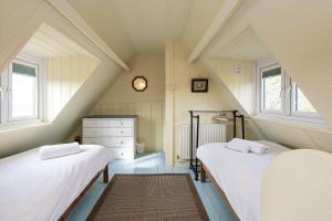 two beds in a attic room with two windows at Cable Cottage in Llanrhyddlad