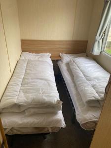 two beds in a small room with white sheets at 8 Berth Caravan At The Seaside Of Haven Hopton-on-sea In Norfolk Ref 80065f in Great Yarmouth