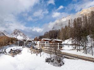 a resort in the snow with a mountain at Hotel Des Alpes in Cortina dʼAmpezzo
