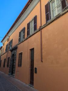an orange building with windows and a door on a street at Cozy Home Away from Home in Tarquinia