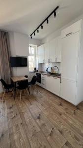uma cozinha com armários brancos e uma mesa e cadeiras em CityCenterApartments-M32-8C em Bielsko-Biala