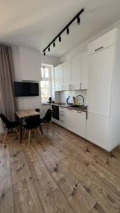 uma cozinha com armários brancos e uma mesa com cadeiras em CityCenterApartments-M32-8C em Bielsko-Biala