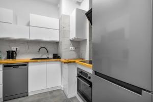a white kitchen with white cabinets and a sink at Złoty Potok Chic Studio in Warsaw