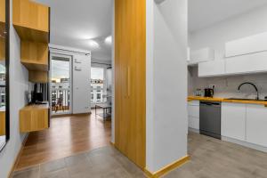 a kitchen with white walls and wooden cabinets at Złoty Potok Chic Studio in Warsaw