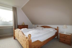 een slaapkamer met een houten bed en een raam bij Haus Bonken - a72764 in Wyk auf Föhr