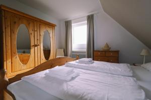 een slaapkamer met 2 bedden met witte lakens en een dressoir bij Haus Bonken - a72764 in Wyk auf Föhr