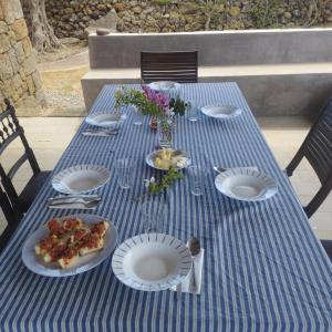een blauwe tafel met borden met eten en bloemen erop bij IL VIGNETO in Pantelleria