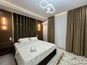 - une chambre avec un grand lit et des draps blancs dans l'établissement ЖK Керуен Сарай, à Türkistan