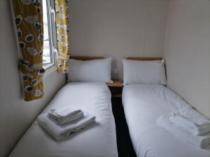 two beds in a small room with towels on them at Ivy cottage - Parking and outdoor area in Kent