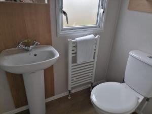 a bathroom with a sink and a toilet and a window at Ivy cottage - Parking and outdoor area in Kent