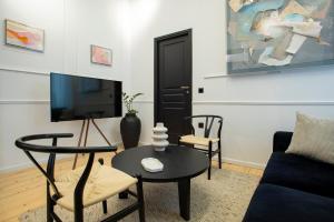 a living room with a tv and a table and chairs at Stoa House Airport in Koropi