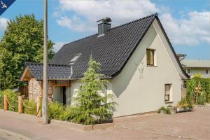 ein kleines weißes Haus mit schwarzem Dach in der Unterkunft Ferienhaus Becker Ferienwohnung Brücke in Heringsdorf