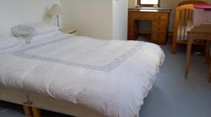 1 dormitorio con cama blanca y escritorio en 405 Tigh Bhrendain Renvyle, en Renvyle