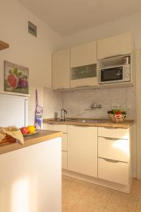 a kitchen with white cabinets and a microwave at Apartment Beti in Lopud