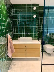 La salle de bains carrelée de couleur verte est pourvue d'un lavabo et de toilettes. dans l'établissement New appartment with art collection, à Vilnius