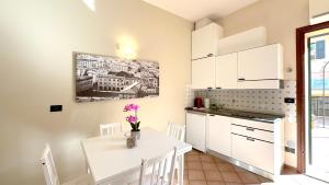 una cucina con armadi bianchi e un tavolo con fiori di Int 12 - Appartamento dei Gerani a Bologna