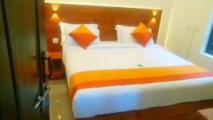 a bedroom with a large bed with orange and orange pillows at CJ Cottage Munnar - Near Attukal Waterfalls, Athukad Tea Estate (CJ Hotels & Resorts) in Devikolam