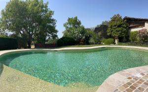 a swimming pool with blue water in a yard at Mas de JANNE in Cléon-dʼAndran
