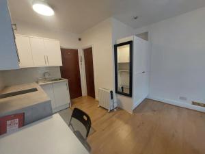 Una cocina con gabinetes blancos y una mesa y sillas. en Newly refurbished studio, en Londres
