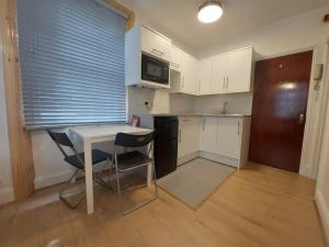 Una pequeña cocina con una mesa y dos sillas. en Newly refurbished studio, en Londres