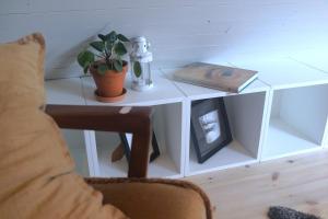 einen weißen Beistelltisch mit einer Pflanze und einem Buch in der Unterkunft Loft Apartment at Isola Gård on the middle of Öland in Färjestaden