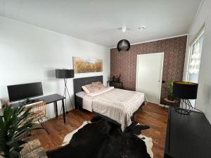 ein Schlafzimmer mit einem Bett und einem TV in der Unterkunft Modern & Stylish 2BR Apartment with Sauna, Terrace and Free Private Parking in Lahti