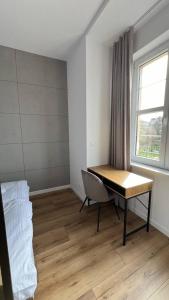 um quarto com uma secretária, uma cama e uma janela em CityCenterApartments/M32/8B em Bielsko-Biala