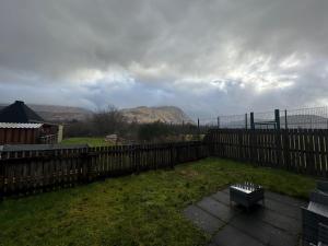 a backyard with a wooden fence and a bench at Benlochy Cottage in Fort William