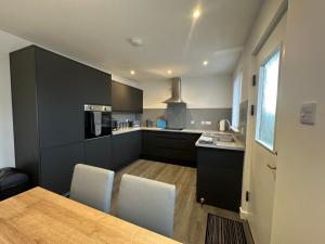 a kitchen with black cabinets and a table and chairs at Benlochy Cottage in Fort William