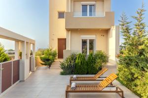 Un patio con dos bancos frente a una casa. en Villa Carpe Diem - 2BR - 300m to Beach, en Heraklion