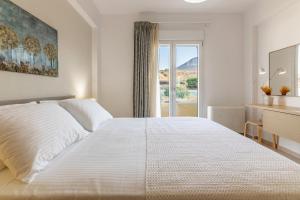 Un dormitorio con una cama blanca y un escritorio y una ventana. en Villa Carpe Diem - 2BR - 300m to Beach, en Heraklion