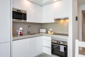 eine Küche mit weißen Schränken und Geräten aus Edelstahl in der Unterkunft Kasino II 1º A in Monte Gordo + 10 Fotos