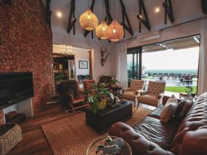 a living room with leather furniture and a fireplace at Otjiwa Mountain Lodge in Otjiwarongo