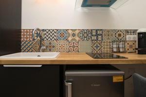 uma cozinha com um lavatório e um balcão com azulejos em Grand studio industriel dans le centre historique em Poitiers