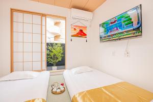 a room with two beds and a flat screen tv at KYARA HOUSE A in Tokyo