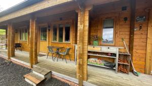 Cabaña de madera con porche con mesa y sillas en Blossom Cabin - Little log Cabin in Wales en Newtown
