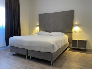 1 dormitorio con 1 cama blanca grande y 2 almohadas en Hotel l'Etrusco - San Vincenzo, en San Vincenzo