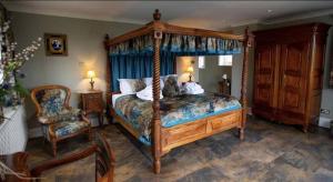 a bedroom with a canopy bed and a chair at Burtree Country House and Retreat in Thirsk