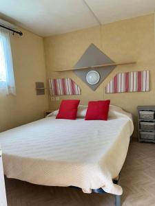 1 dormitorio con 1 cama grande y 2 almohadas rojas en Mobilhome, en Castillonnès