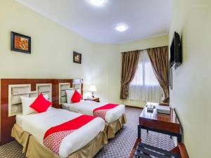 two beds in a hotel room with red pillows at Zenith Smart Vacation Homes, Sharjah in Sharjah
