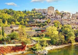 a view of a town with a river and buildings at Charming typical stone house with modern amenities in Chauzon