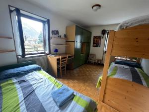 a bedroom with two beds and a desk and a window at Casa Ognano (Pellizzano) in Pellizzano
