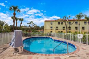 - une piscine en face d'un bâtiment avec des palmiers dans l'établissement Quality Inn Sarasota I-75, à Sarasota