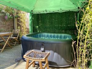 uma banheira de hidromassagem sob uma tenda verde com um banco em SoHot Stays Stylish & Cosy with Hot Tub & Log Burner, Margate em Margate