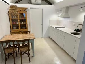 a kitchen with white cabinets and a wooden table at Brava Apartaments casa centro Begur in Begur