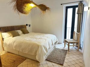 a bedroom with a bed and a chair and a window at Brava Apartaments casa centro Begur in Begur