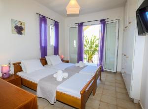 羅達的住宿－S&C Kosmos Beach Resort，一间卧室设有两张床和一个带紫色窗帘的窗户。