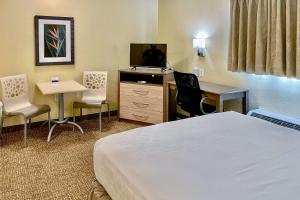 um quarto de hotel com uma cama, uma secretária e uma televisão em Suburban Studios Fort Myers Cape Coral em Fort Myers