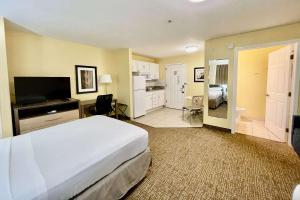 um quarto de hotel com uma cama e uma televisão em Suburban Studios Fort Myers Cape Coral em Fort Myers