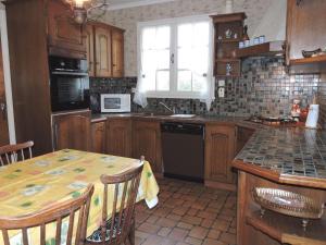 a kitchen with wooden cabinets and a table with a microwave at Large holiday home with garden in Brittany in Hénansal